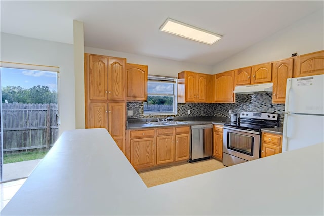 kitchen with a sink, stainless steel appliances, under cabinet range hood, light tile patterned floors, and tasteful backsplash