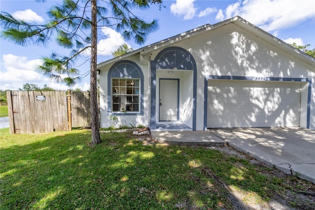 view of front of home with stucco siding, fence, driveway, a front yard, and an attached garage