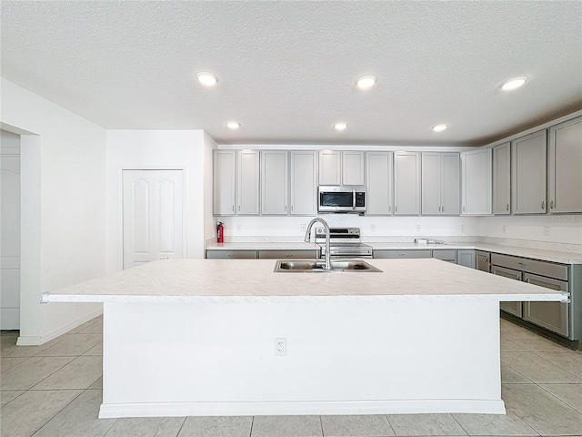 kitchen with a textured ceiling, a kitchen island with sink, and sink