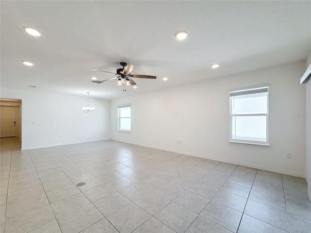 tiled spare room featuring ceiling fan with notable chandelier