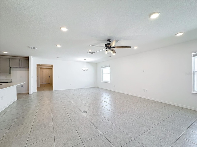 interior space with a textured ceiling, light tile patterned floors, and ceiling fan with notable chandelier