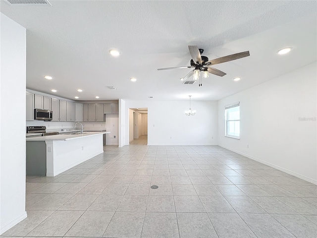 kitchen with sink, light tile patterned floors, gray cabinets, appliances with stainless steel finishes, and ceiling fan with notable chandelier