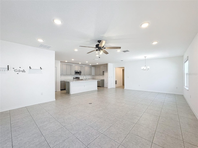 unfurnished living room with sink, light tile patterned flooring, and ceiling fan with notable chandelier