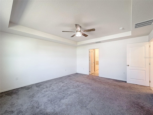 carpeted spare room featuring ceiling fan, a textured ceiling, and a raised ceiling