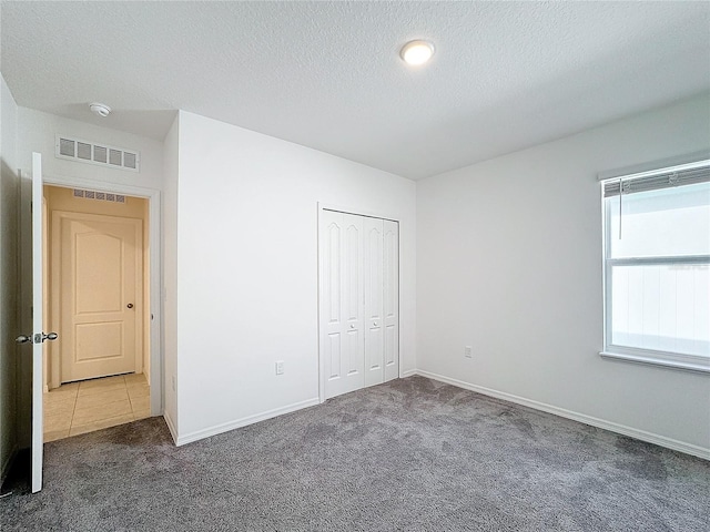 unfurnished bedroom featuring a closet, a textured ceiling, and dark colored carpet