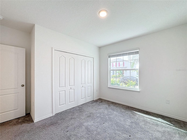 unfurnished bedroom featuring a closet, a textured ceiling, and carpet flooring