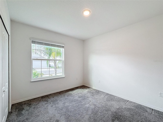 unfurnished bedroom featuring a closet and dark colored carpet