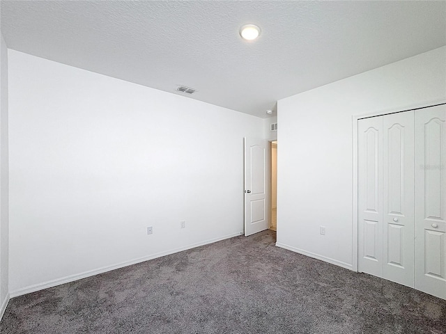 unfurnished bedroom featuring a closet, a textured ceiling, and dark colored carpet