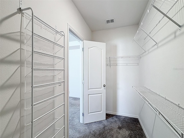 spacious closet featuring dark carpet