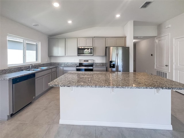 kitchen featuring a center island, appliances with stainless steel finishes, vaulted ceiling, and gray cabinets