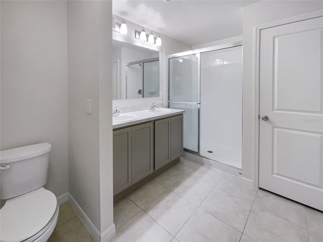 bathroom featuring toilet, a shower with shower door, vanity, and tile patterned floors