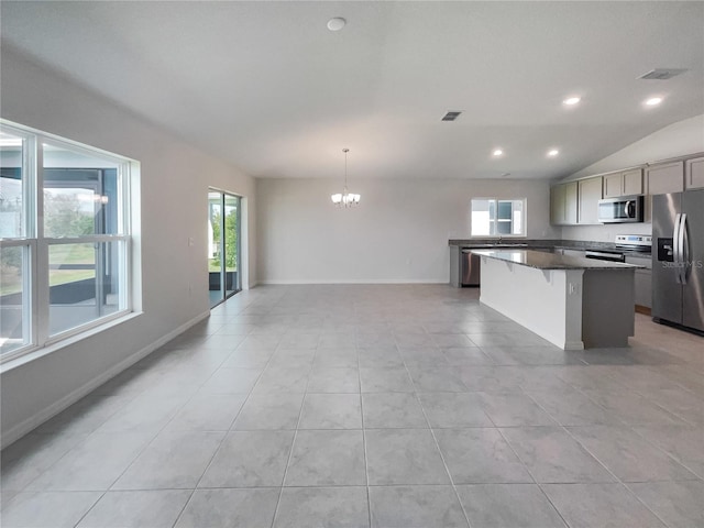 kitchen with gray cabinetry, appliances with stainless steel finishes, a center island, lofted ceiling, and decorative light fixtures