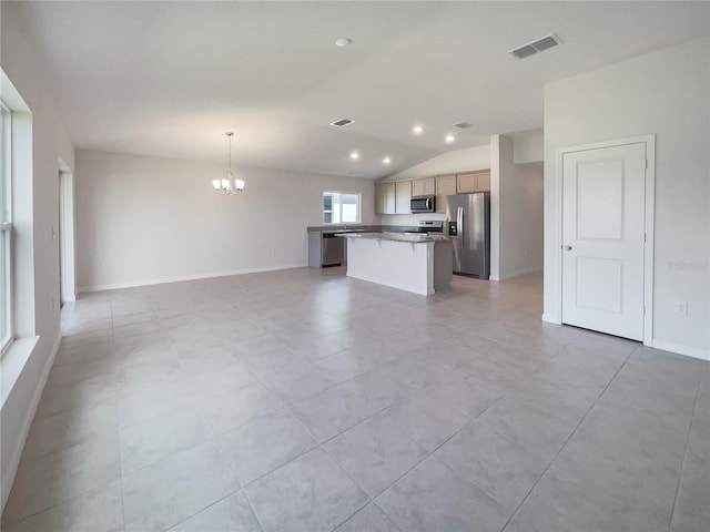 interior space featuring appliances with stainless steel finishes, a kitchen island, hanging light fixtures, lofted ceiling, and a notable chandelier