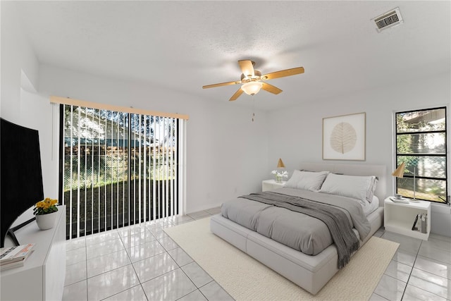 tiled bedroom featuring a textured ceiling, multiple windows, access to outside, and ceiling fan