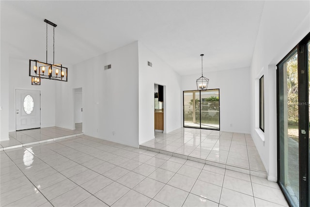 entrance foyer featuring light tile patterned floors, a wealth of natural light, and an inviting chandelier