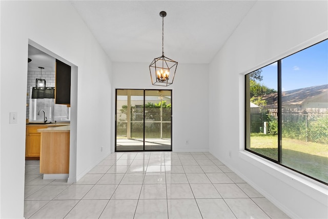 spare room featuring a wealth of natural light, a notable chandelier, a mountain view, and light tile patterned floors