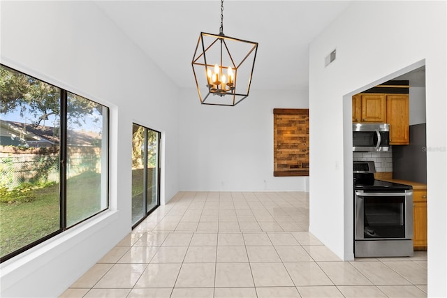 interior space featuring light tile patterned flooring, a notable chandelier, and a towering ceiling