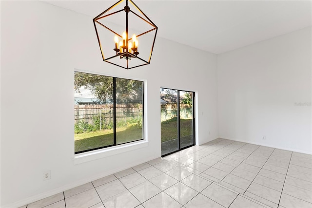 unfurnished room with a healthy amount of sunlight, a chandelier, and light tile patterned floors