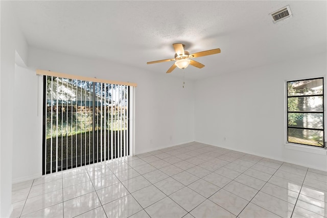 tiled spare room with a wealth of natural light, a textured ceiling, and ceiling fan