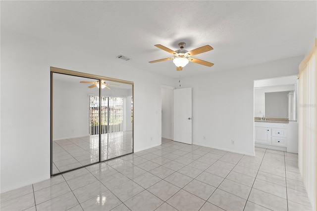 unfurnished room featuring sink, ceiling fan, a textured ceiling, and light tile patterned floors