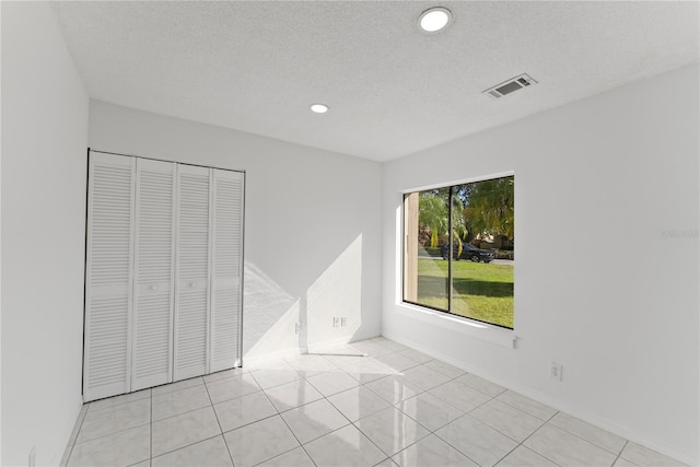 unfurnished bedroom with light tile patterned flooring, a textured ceiling, and a closet