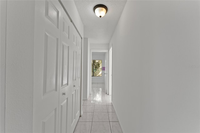 hallway featuring light tile patterned flooring and a textured ceiling