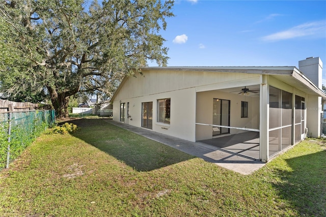 back of property with a sunroom, ceiling fan, a lawn, and a patio area