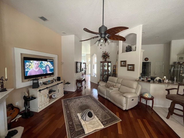 living room with dark hardwood / wood-style flooring, a textured ceiling, and ceiling fan