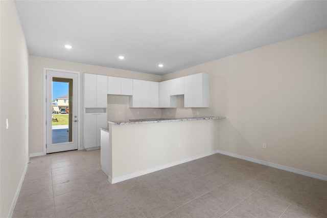 kitchen with white cabinets, light stone counters, and light tile patterned floors