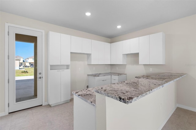 kitchen with white cabinetry, light stone countertops, and kitchen peninsula