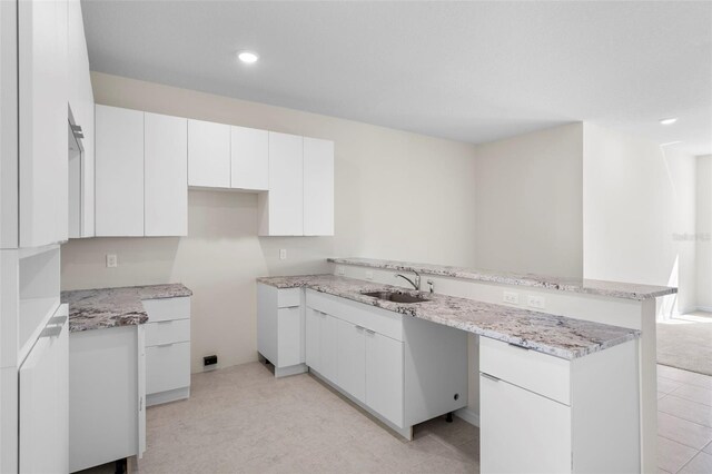 kitchen featuring light carpet, sink, and white cabinets