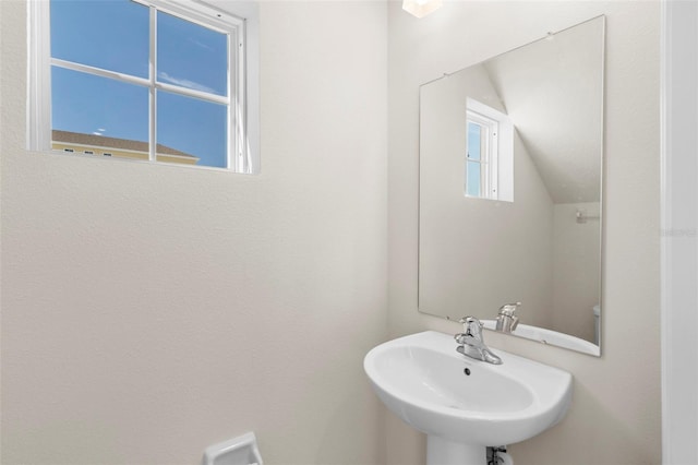 bathroom featuring vaulted ceiling, sink, and plenty of natural light