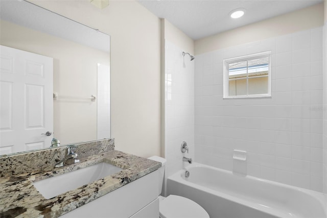 full bathroom featuring vanity, tiled shower / bath combo, and toilet