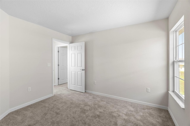 spare room featuring light carpet and a textured ceiling