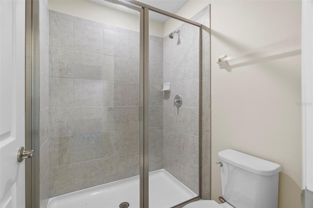 bathroom featuring a shower with door and toilet