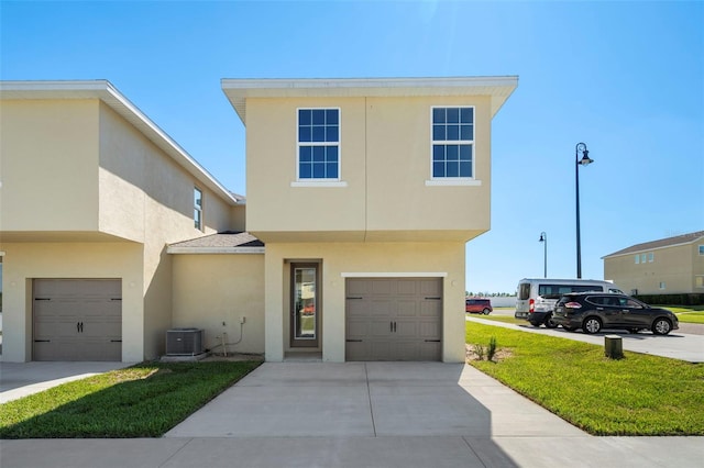 view of front of house with a front yard, central AC unit, and a garage