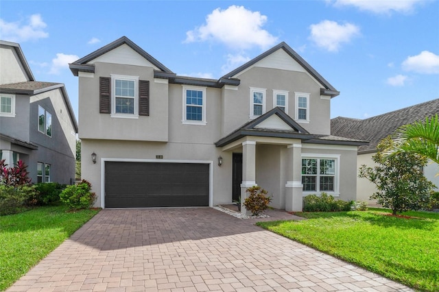 view of front of house featuring a garage, a front lawn, decorative driveway, and stucco siding