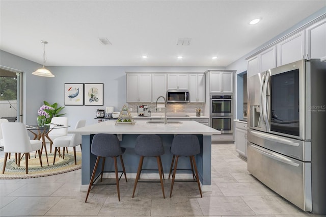 kitchen featuring stainless steel appliances, light countertops, visible vents, a sink, and a kitchen bar