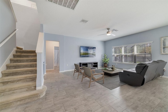 living room featuring stairway, visible vents, and a ceiling fan