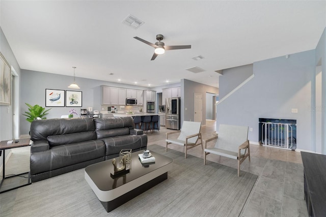 living room with baseboards, visible vents, a ceiling fan, and recessed lighting