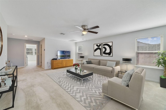 living area featuring light carpet, a ceiling fan, visible vents, and baseboards