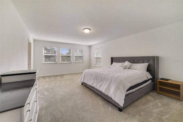 bedroom with light colored carpet, a textured ceiling, and baseboards