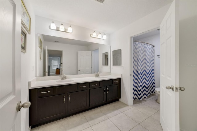 full bath with double vanity, tile patterned flooring, a sink, and toilet