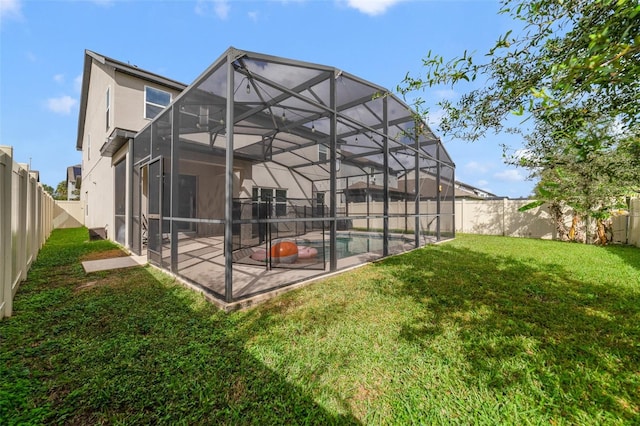 rear view of house with a yard, a patio, stucco siding, a lanai, and a fenced backyard