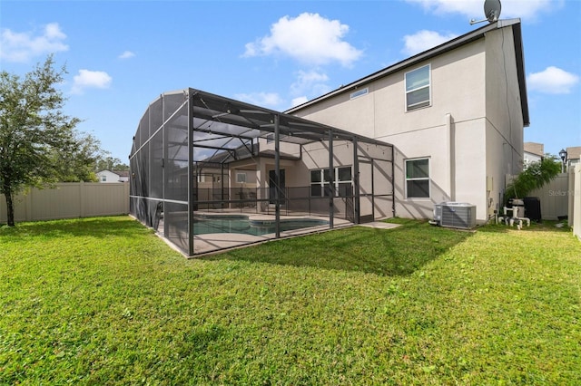 rear view of house with glass enclosure, a fenced backyard, a yard, central AC, and stucco siding