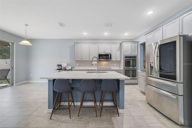 kitchen with stainless steel appliances, a sink, visible vents, light countertops, and tasteful backsplash