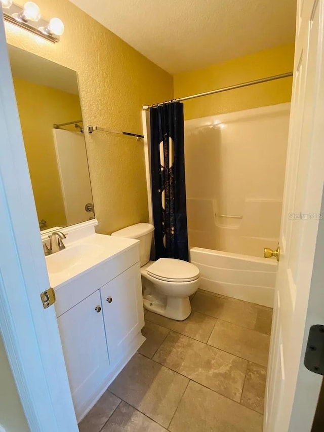 full bathroom featuring vanity, toilet, shower / bath combo with shower curtain, and a textured ceiling