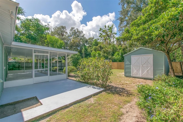 view of yard featuring a patio area, a sunroom, and a storage shed