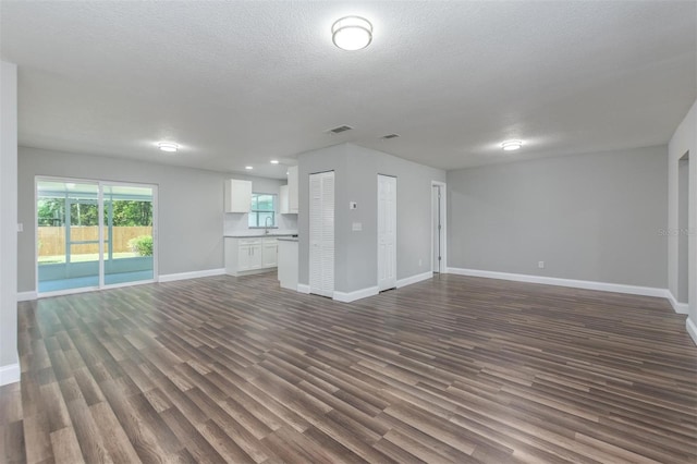 unfurnished living room with a textured ceiling, dark hardwood / wood-style floors, and sink