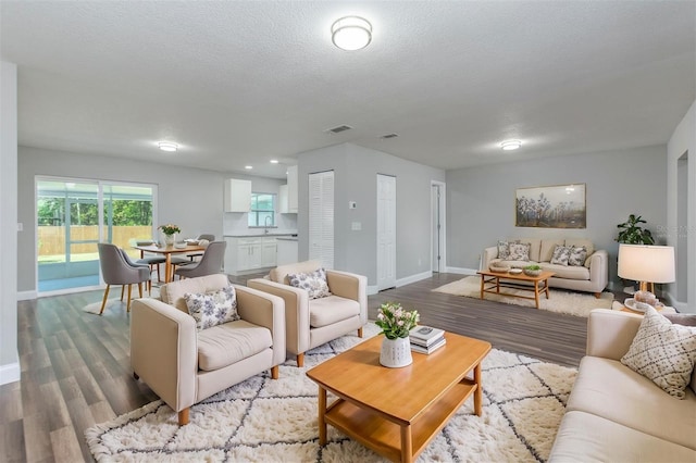 living room featuring a textured ceiling, light wood-type flooring, and sink